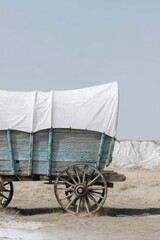 Vintage Covered Wagon with Weathered Blue Wood Parked in a Desert Field for History Education and Pioneer Concept with Minimalism and Copy Space Background