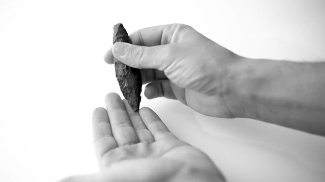 Authentic Paleolithic Biface Spear Head from Algerian Desert Held in Hand. slow motion. black and white video