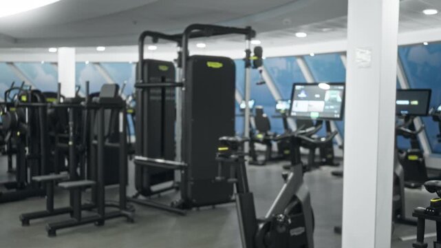 Gym interior with defocused bokeh exercise machines and soft blur background interior; background backplate copyspace calm.