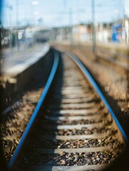 Obraz premium Railway Tracks Leading Into Blurred Station Background for Transportation Concept and Travel Logistics Advertising with Abstract Depth of Field and Copy Space