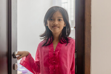 A beautiful Indonesian student girl wearing a traditional Kebaya Dress at home
