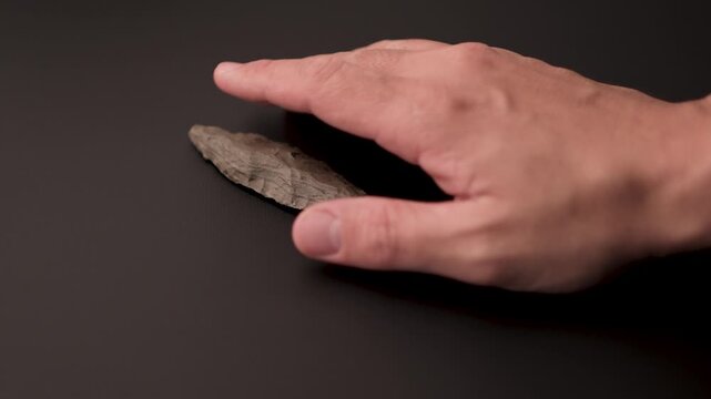 Authentic Paleolithic Biface Spear Head from Algerian Desert Held in Hand. dark style
