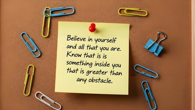 Motivational handwritten quote pinned to a cork board surrounded by colorful paper clips and binder clips for office inspiration.