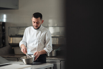 Fototapeta premium Professional pastry chef smiling while stirring batter at station