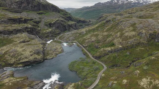 Rallarvegen Trail (Navvy Road) Passing Through The Mountain Hills And River In Hardangervidda National Park, Norway. - wide shot