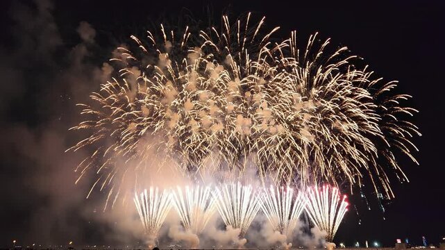 Intense barrage of beautiful colorful celebratory pyrotechnic fireworks bursting rapidly high above the ground against a dark evening sky holiday, sky, year