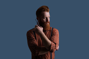 Man beard haircut by hairdresser at barbershop. Handsome barber using retro scissors while cutting hair. Modern barbershop haircut. Bearded hipster barber isolated on grey. Male beauty