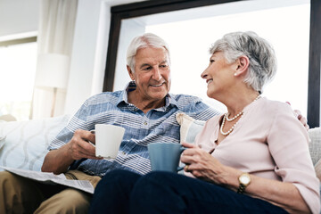 Talking, coffee and senior couple on sofa in home for bonding, love and reading together....