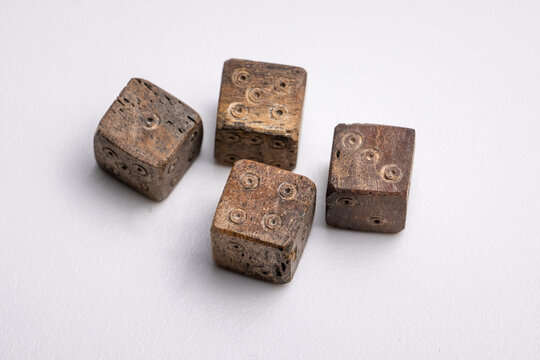 Close-up of Roman-era dice carved from bone, featuring worn edges and hand-carved pips. These ancient gaming pieces reflect leisure and gambling practices in the Roman Empire.