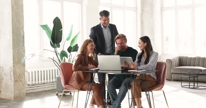 Happy colleagues collaborate around laptop in office, reviewing new business platform or data, sharing ideas, working on joint online project. Team collaboration, group discussion, digital workflow