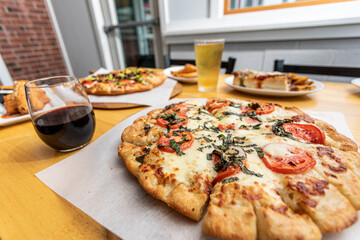 A margherita pizza on a table with other food and beer at a bright modern pizza restaurant 