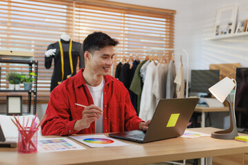 Young asian man fashion designer working on laptop
