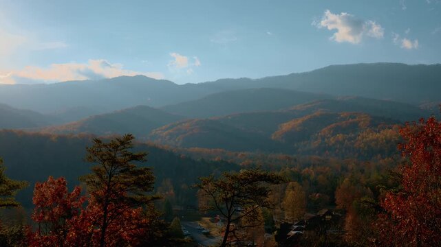 A wide panoramic view of mountain ridges covered in colorful autumn forest under soft golden-hour light. Seasonal beauty, nature, and a calm outdoor atmosphere.