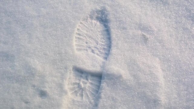 One distinct boot print left deep in clean white fluffy snow during cold winter weather