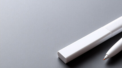 Close up of a white stylus and rectangular accessory on a tabletop minimal product scene.
