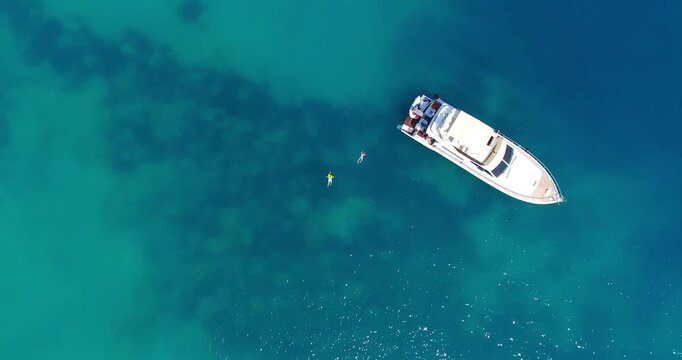 Cyprus, Pafos, 4K Aerial View of Two Divers Swimming Near a Luxury Boat in Clear Blue Water