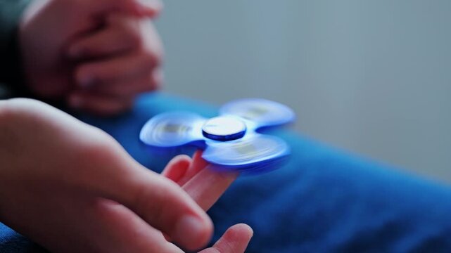 Blue fidget spinner spinning smoothly on kids finger indoors showing calm motion
