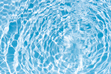 Obraz premium Blue water with ripples on the surface. Defocus blurred transparent blue colored clear calm water surface texture with splashes and bubbles. Water waves with shining pattern texture background.