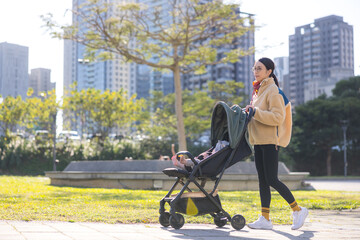 Mother walking with baby stroller at park