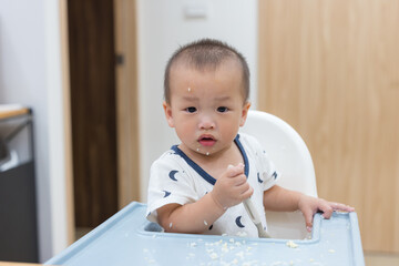 Little baby eating food independently at home