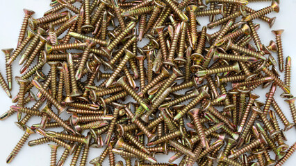 Pile of yellow zinc plated self-drilling screws isolated on white background.