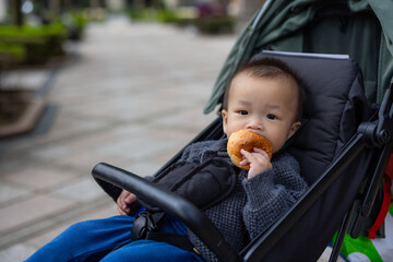 Toddler enjoying bread during ride in stroller