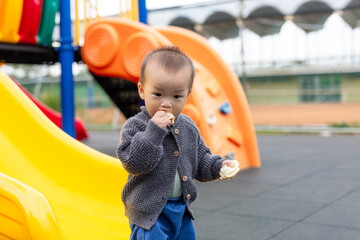 Toddler enjoying bread while playing at playground