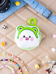 A close-up of a soft, green plush wallet featuring a fun white monster design.