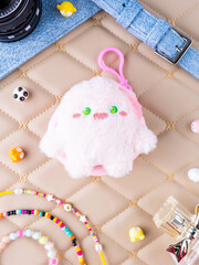 A close-up of a soft pink plush wallet featuring a fun and adorable monster design