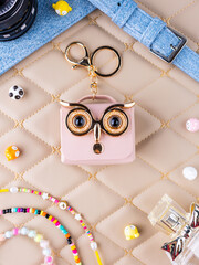 A close-up of a small pink leather mini bag featuring an owl design with bright, expressive eyes