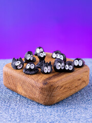A close-up of a set of miniature interior figurines of black Susuwatari (soot sprites) placed on a wooden stage