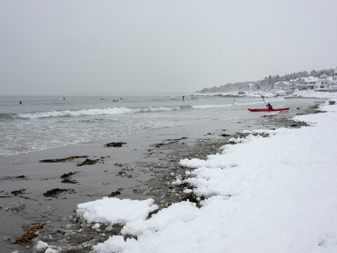 Kayaker launching into the surf at Higgins Beach in Scarborough, Maine