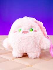 A close-up of a soft pink plush wallet featuring a fun and adorable monster design