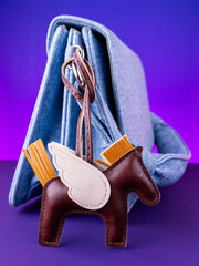 A close-up view of a brown leather horse keychain accessory designed as a bag charm on blue bag