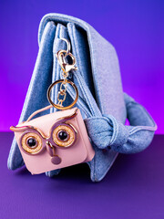 A close-up of a small pink leather mini bag featuring an owl design with bright, expressive eyes on blue bag