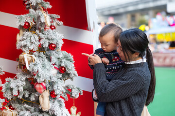 Mother holding baby near christmas tree outdoor