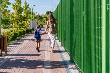 Parent escorting young student to school while holding hands, symbolizing education, care, and family support © Koldo_Studio