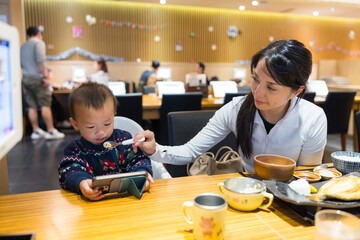 Mother and baby watching smartphone while eating together