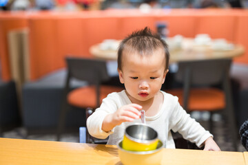 Baby playing with tableware at restaurant