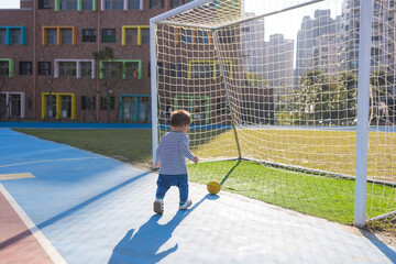 Little son playing football shooting goal outdoors