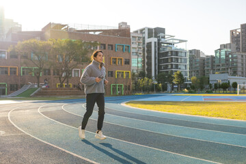 Female athlete running on running track outside