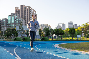 Young female athlete running on track outdoors