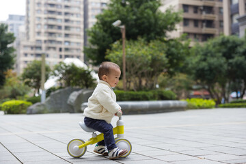Toddler riding bicycle learning outdoors in park