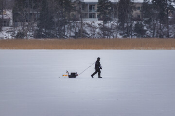 Ice Fisherman Standing on a Frozen Lake with Fishing Gear.
