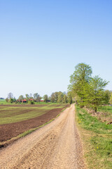 Long straight gravel road in a rural landscape at springtime