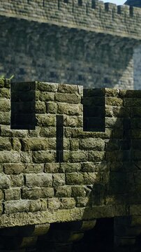 Mosscovered stone parapet with crenelated silhouette, weathered masonry and shadowed walkway historic fortress mood, textured lichen, arch and gate hints,