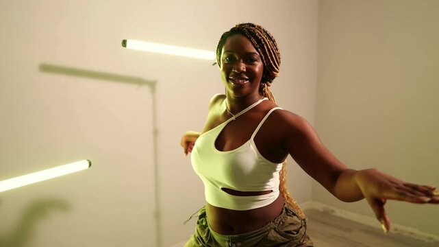 Energetic african woman with blonde braids performing a dynamic afrodance routine. Passionate dancer moving rhythmically in a studio