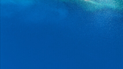 Top view aerial shot of deep blue freshwater reservoir surface with gentle ripples and sunlight reflections. © Jitti