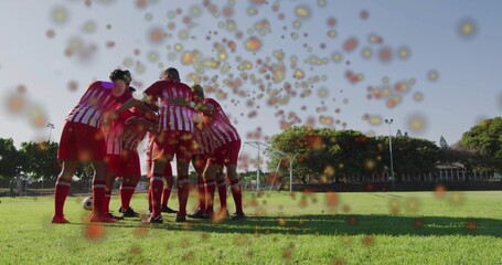Huddling male soccer players linking arms on pitch, showing red-striped kits, soccer ball, bokeh © vectorfusionart