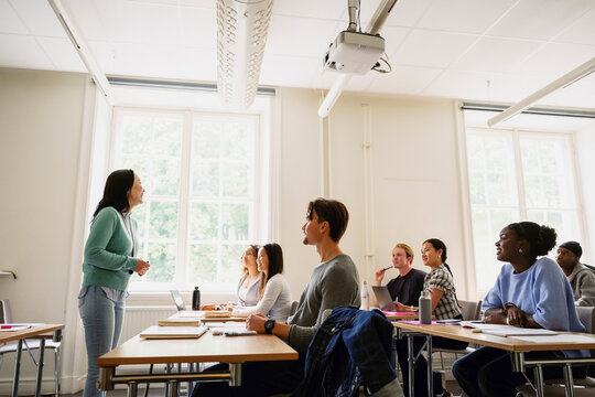 Female professor teaching adult students sitting in classroom at college